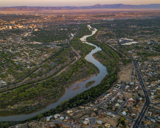 Image of river running through a city toward mountains in background.