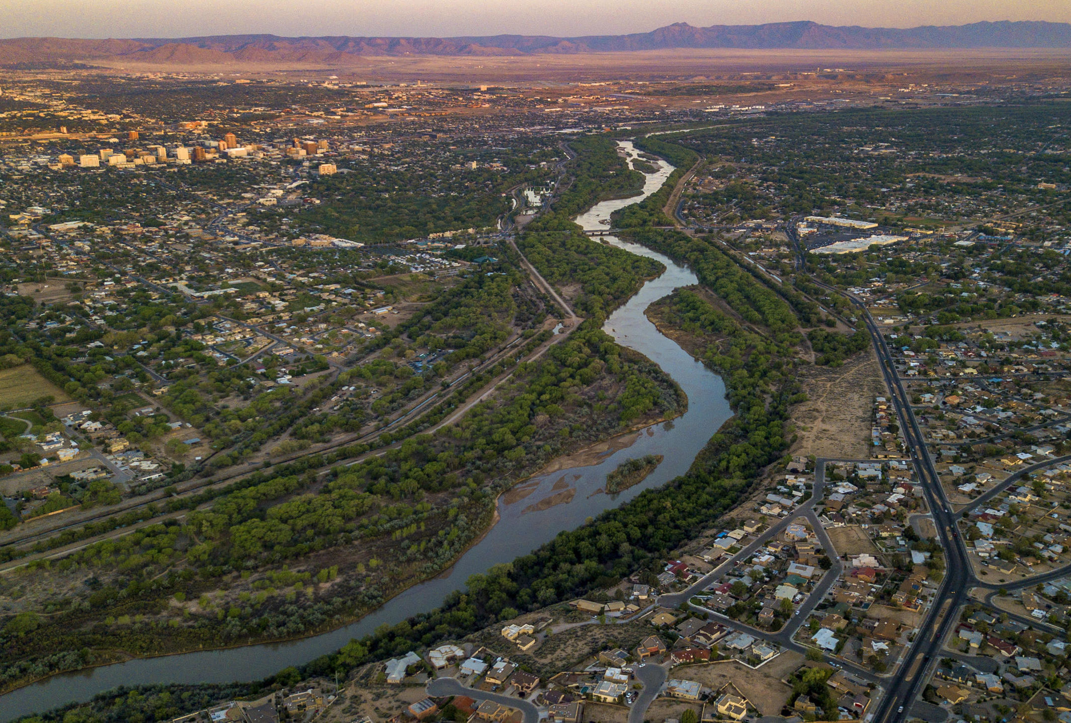 Image of river running through a city toward mountains in background.