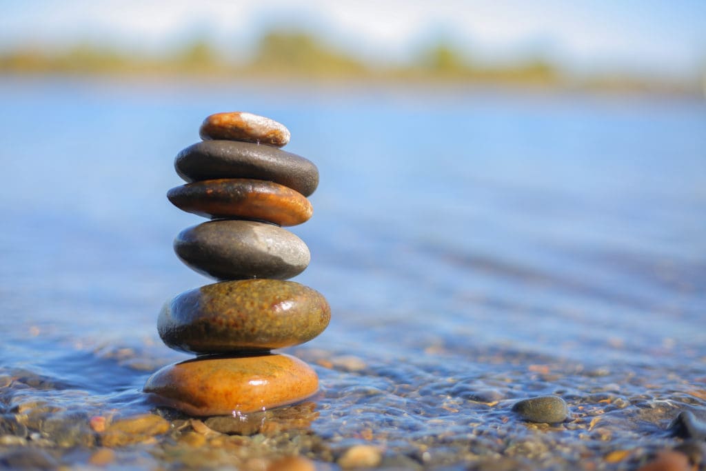 Close up photograph of a cairn (stack of stones) in the shallow banks of a river.
