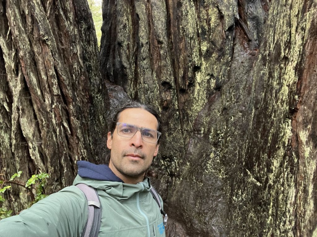 A photo of José next to a tree