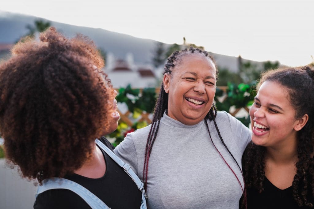 Mother having a fun and laughing moment with her daughters at a family meal outdoors.