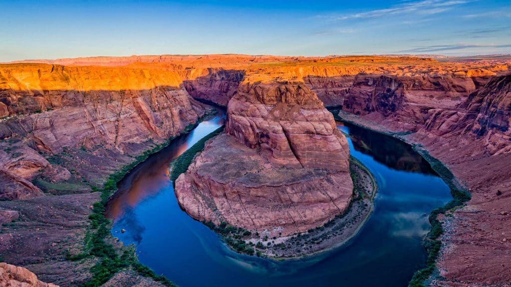 Photograph of Horseshoe Bend along the Colorado River. Blue river snaking around red rock formations.