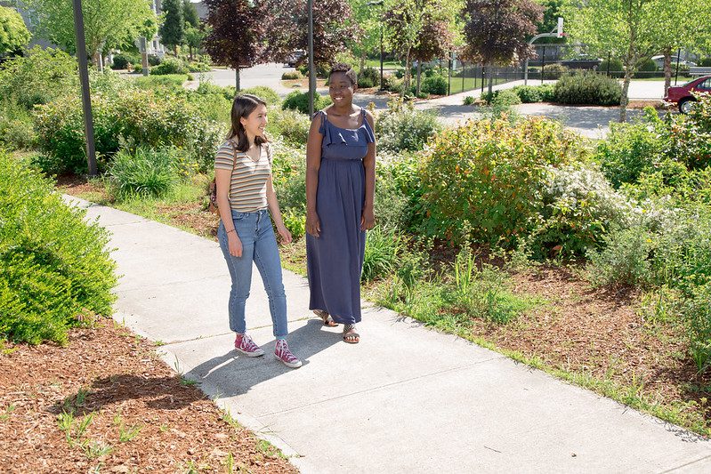 photo of women walking in a city with greenery around them