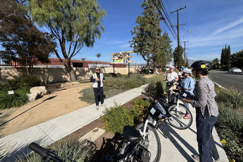 a group of people on bikes at a greenway listening to a speaker